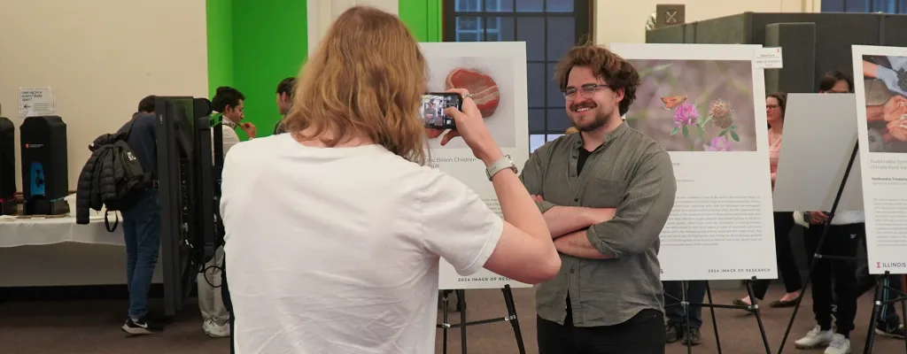 graduate student taking photo of another graduate student standing in front of is Image of Research poster