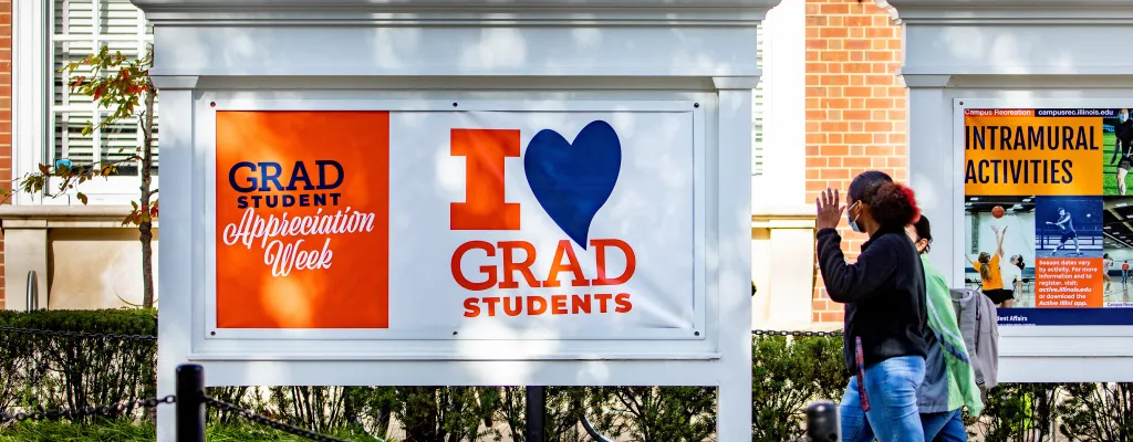 Students walking by Graduate Student Appreciation Week banner