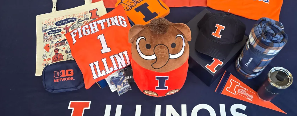 a selection of University of Illinois branded prizes including tote bag, tee shirts, baseball cap, thermal travel mug and plush wooly mammoth