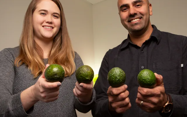 Graduate student Caitlyn Edwards and professor Naiman Khan hold avocados 
