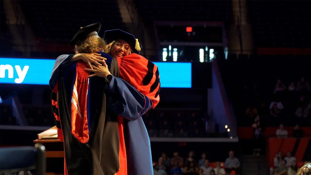 graduate and faculty advisor embrace in celebration